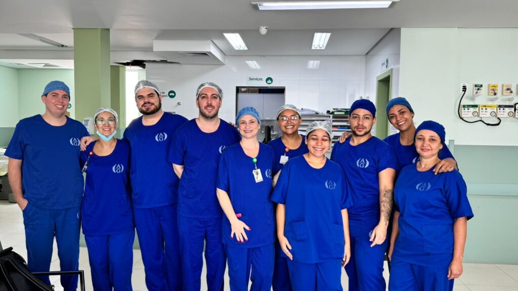 Equipe de dez profissionais do Hospital Arnaldo Gavazza com jaleco azul. Ao fundo, o corredor do hospital.