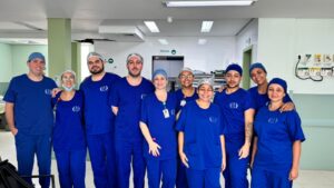 Equipe de dez profissionais do Hospital Arnaldo Gavazza com jaleco azul. Ao fundo, o corredor do hospital.